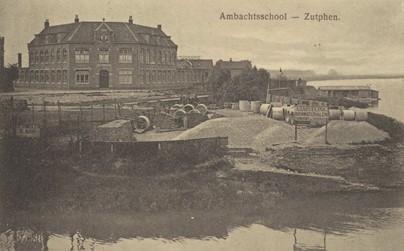 <p>In 1908 werd door de gemeenteraad besloten om bouwterrein en subsidie beschikbaar te stellen voor de bouw van een ambachtsschool op het Hoornwerk. De school werd een jaar later geopend en in de loop der jaren uitgebreid. Op de voorgrond lag aan de IJssel de bouwmaterialenhandel van A. Garvelink (Regionaal Archief Zutphen). </p>
